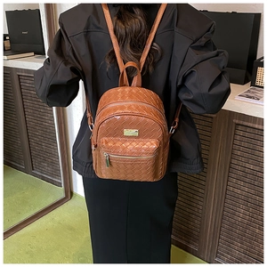 Vista posteriore di una donna con zaino in pelle intrecciata marrone e placca logo dorata