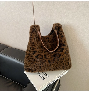 Detail of soft leopard print faux fur tote bag with brown leather strap on books
