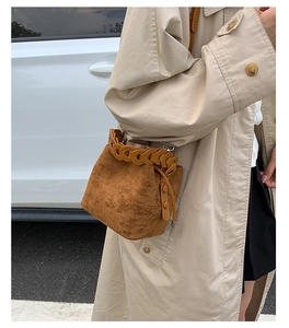 Detail view of brown suede bucket bag with leather woven trim and drawstring closure