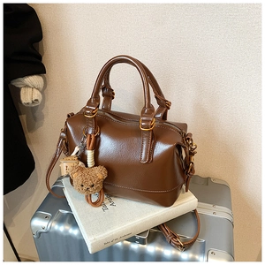 Detail of dark brown boston bag showing leather texture and cute plush bear charm