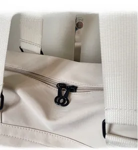Detail of smooth double zipper with black circular metal pulls on off-white tote bag