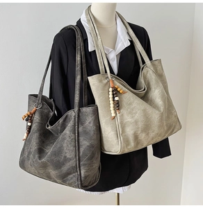 Close-up of retro tote bags in dark grey and khaki with ethnic wooden bead tassels