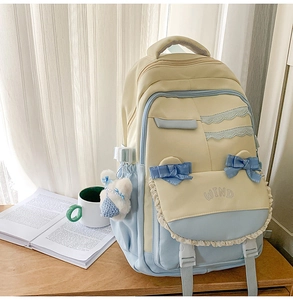 Detail of preppy nylon backpack with lace trim, blue bows and cute white bear keychain