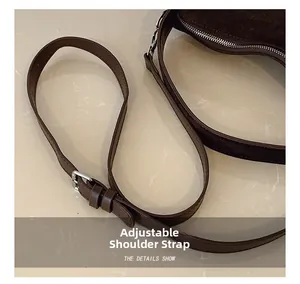 Detail view of the adjustable brown suede bag strap with silver metal buckle