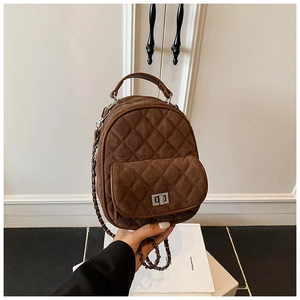Detail of a brown quilted mini backpack featuring matte texture and chain shoulder strap