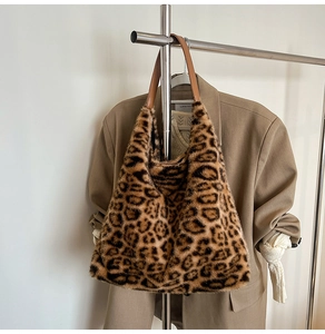 Close-up of leopard print faux fur tote bag with brown leather handles on a hanger