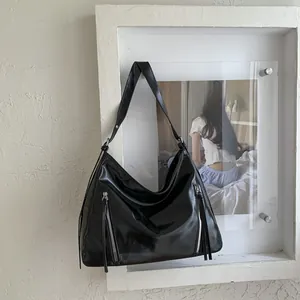 Detail of black glossy leather hobo bag with dual vertical metal zippers and wide strap