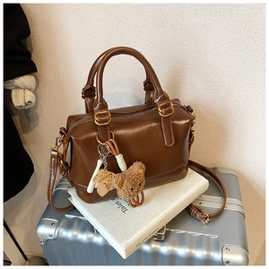 Detail view of brown vintage Boston bag with oil wax leather texture and plush bear charm