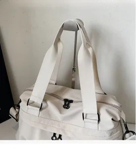 Close-up of beige travel bag showing dual zippers and durable webbing handle detail