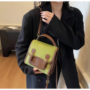 Close-up of green felt backpack with brown leather straps and metal buckle details
