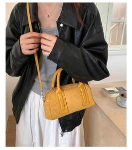Detail shot of a yellow suede crossbody bag with minimalist handle and zip closure