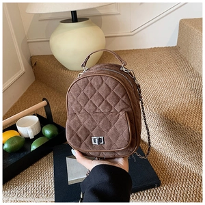 Detail of brown quilted suede mini backpack with metallic twist lock and chain strap