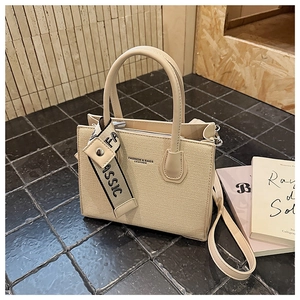 Détail du sac bandoulière beige tissé avec poignées en cuir et bandoulière classique large