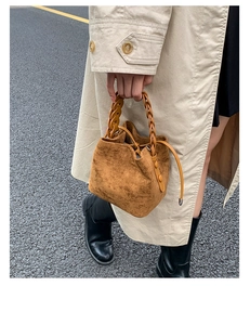 Detail of caramel suede bucket bag with woven ring handle and drawstring closure