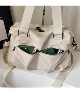 Detail view of large beige tote bag with front zipper pockets holding phones and bottles