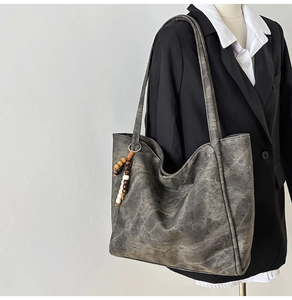 Detail of grey vintage textured tote bag with multi-color beaded charm on mannequin