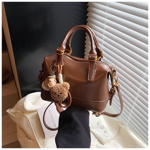 Detail of classic brown Boston bag with cute teddy bear charms and gold hardware