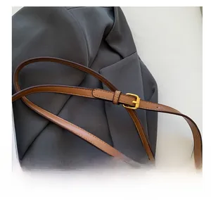 Détail de la bandoulière réglable en cuir marron avec boucle dorée sur un sac seau imprimé