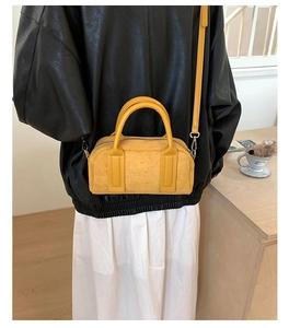 Detail of yellow pebbled leather bowling bag with silver hardware and adjustable strap