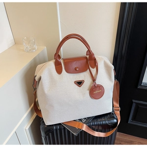 Detail view of large canvas tote bag with leather straps on a vintage suitcase