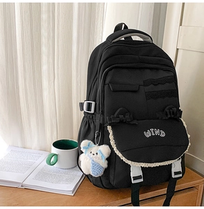 Detail of high-capacity preppy backpack with lace trim, WIND embroidery and plush bear charm