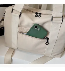 Detail view of large capacity cream travel bag featuring front zipper pocket for phone