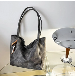 Detail of grey matte tote bag showing large capacity structure and wood bead charm