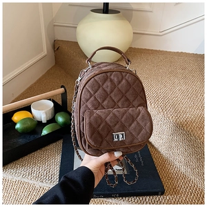 Detailed view of brown quilted suede backpack featuring silver twist lock and chain straps