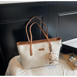 Dettaglio della borsa tote a scacchi con finiture in pelle marrone e ciondolo a coniglietto