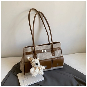 Detail of a brown tote bag with marble texture, metal twist lock, and a cute teddy bear charm