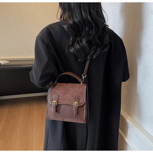 Detail shot of the dark brown vintage matte backpack worn with a black coat