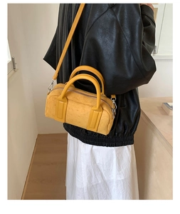 Detail of yellow suede Boston handbag with dual handles and detachable shoulder strap