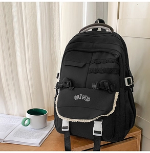 Detail of black academic backpack featuring lace trim, pleated edges, and WIND embroidery