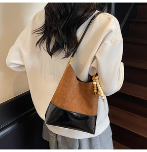Détail du sac porté épaule vintage avec coutures contrastées et breloque en bois