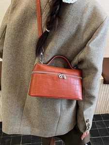 Orange croc-embossed vanity box bag with top handle and strap on grey blazer
