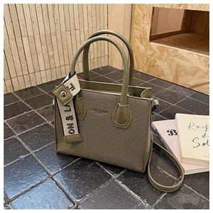 Détail du cabas vert olive avec texture en tissu et logo avec bandoulière tissée chic