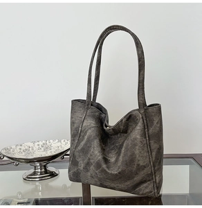Close-up of a charcoal grey tote bag with vintage matte texture on a glass table