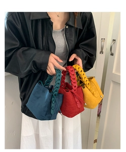 Detailed shot of vintage suede bucket bags in navy blue, red, and yellow with chain handles