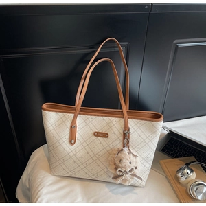 Dettaglio della borsa tote a scacchi con logo del marchio e ciondolo a forma di coniglio di peluche