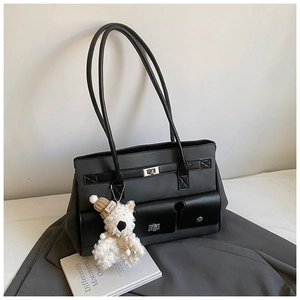 Detail of grey tote bag with black leather straps and a cute plush bear charm