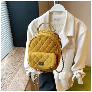 Detail of yellow quilted mini backpack with silver metal lock and chain strap