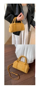 Detail view of mustard yellow suede Boston bag featuring dual handles and thin shoulder strap