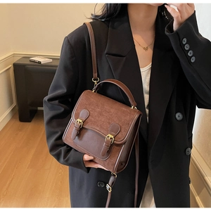Lifestyle view of a vintage brown matte leather backpack styled with a black blazer