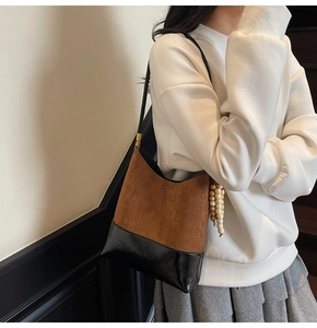 Detail of retro shoulder bag featuring brown suede and black faux leather texture contrast