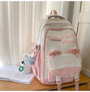 Detailed view of pink and beige backpack featuring lace, bows and a plush bear charm