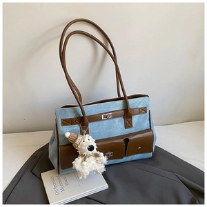 Detail of blue denim tote bag with brown PU leather pocket and plush puppy charm