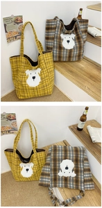 Detail of yellow and brown plaid tote bags featuring cute dog patches on wooden steps