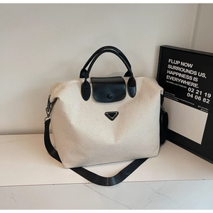 Detail of canvas tote with leather handles, shoulder strap and black brand logo