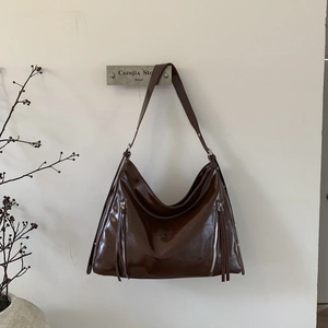 Detail of dark brown glossy leather Hobo bag with side zippers and leather tassels