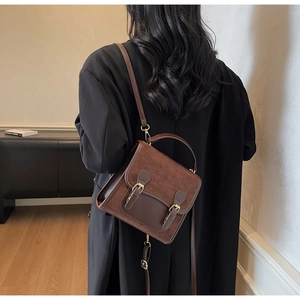 Rear view of brown vintage messenger backpack with dual buckle closure and matte texture